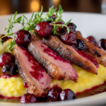 Sliced duck breast with crispy skin fanned over a bed of creamy yellow polenta, topped with cherry gastrique and served with roasted fennel.